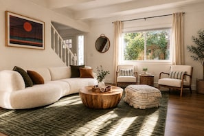 Ein Wohnzimmer mit einer Couch, Sesseln, einem Couchtisch und einer Treppe.