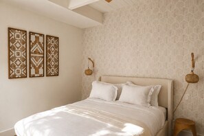 Ein Schlafzimmer mit einem Bett, einer Wandlampe und strukturierter Wandtapete.