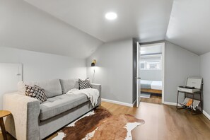 A modern living room with a grey sofa, a cowhide rug, and a small side table with a record player. - Mins to RRG | Hot Tub, Game Room, Fire Pit (Stanton)