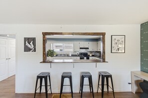 A kitchen with a central island, three stools, and a large mirror above the island. - Mins to RRG | Hot Tub, Game Room, Fire Pit (Stanton)