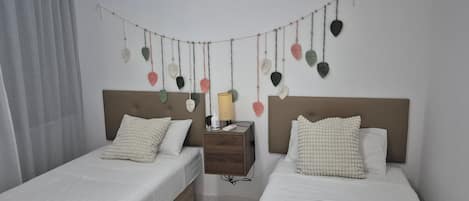 A hotel room with two beds, a nightstand, and a wall-mounted string of decorative leaves.