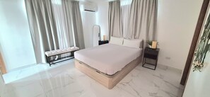 Un dormitorio moderno con una cama grande, un banco, una mesita de noche y un espejo.