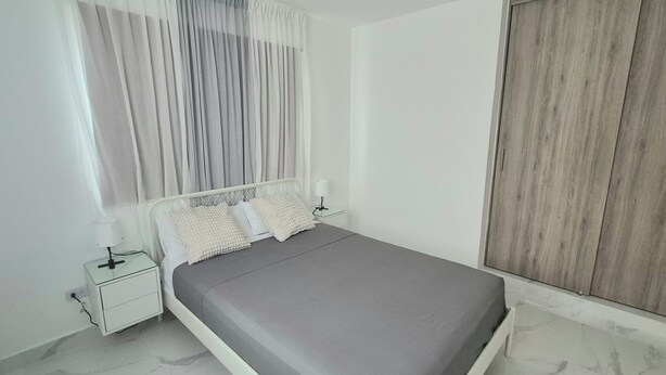 A bedroom with a bed, a bedside table, a lamp, and a wardrobe. - Villa Mar  (Punta Cana)