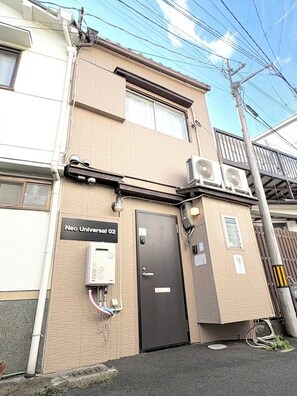 A building with a sign reading 'Neo Universal 02,' a door, and an air conditioning unit. - Neo Universal 02 (Osaka, Konohana Ward, Nishikujo)