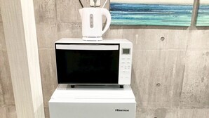 A Hisense refrigerator with a microwave on top, placed against a concrete wall with a painting of a beach scene. - Neo Universal 02 (Osaka, Konohana Ward, Nishikujo)