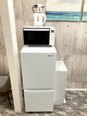 A Hisense refrigerator with a microwave on top, placed against a concrete wall with a painting of a beach scene. - Neo Universal 02 (Osaka, Konohana Ward, Nishikujo)