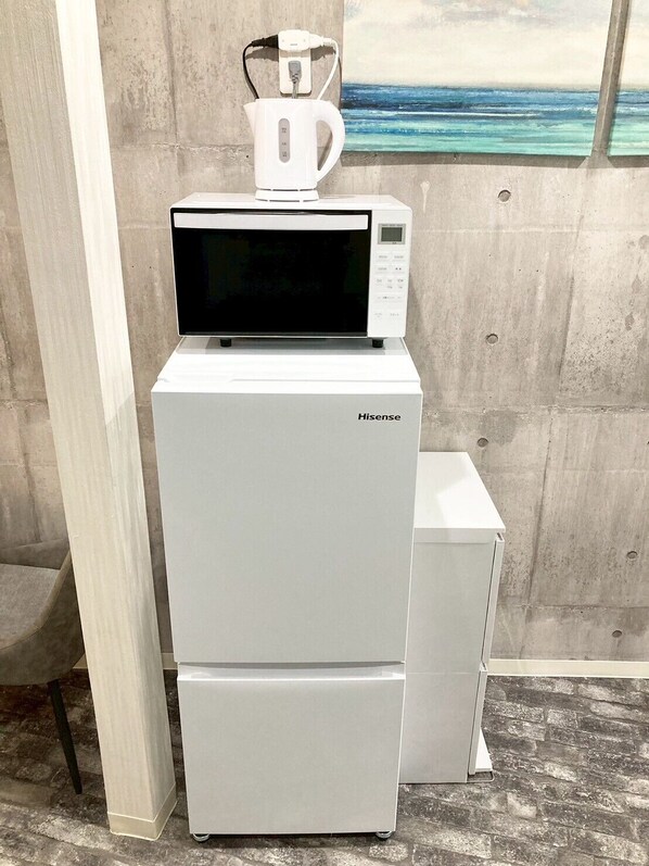 A Hisense refrigerator with a microwave on top, placed against a concrete wall with a painting of a beach scene. - Neo Universal 02 (Osaka, Konohana Ward, Nishikujo)