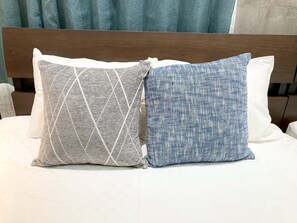Una cama con dos almohadas, una con estampado geométrico y la otra con textura.
