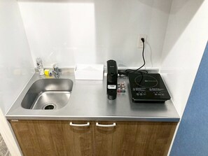 A kitchen with a stainless steel sink, a black induction cooktop, and a white countertop. - Neo Universal 02 (Osaka, Konohana Ward, Nishikujo)