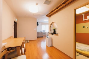 A room with a wooden dining table and chairs, a small kitchen area, and a traditional Japanese sliding door. - Just a short walk from the Shinsaibashi Glico Sign (1 min), Dotonbori (30 seconds), Kuromon Market, Namba Station, Dotonbori, and Ran no Kaku (Osaka)