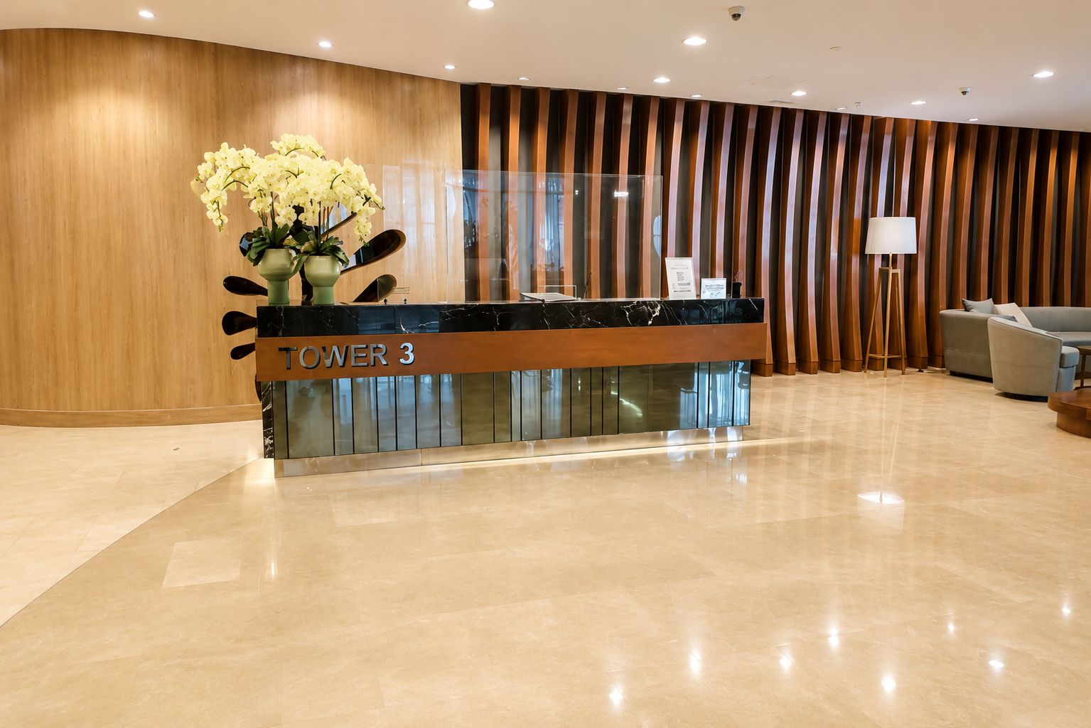 A reception desk labeled 'TOWER 3' with a modern design, a glass partition, and a sofa in the background.