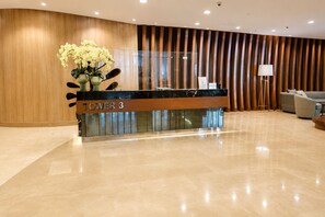 A reception desk labeled 'TOWER 3' with a modern design, a glass partition, and a sofa in the background. - Luxury Pool View Condo Near MOA | Smart Lock | Netflix (Pasay City)