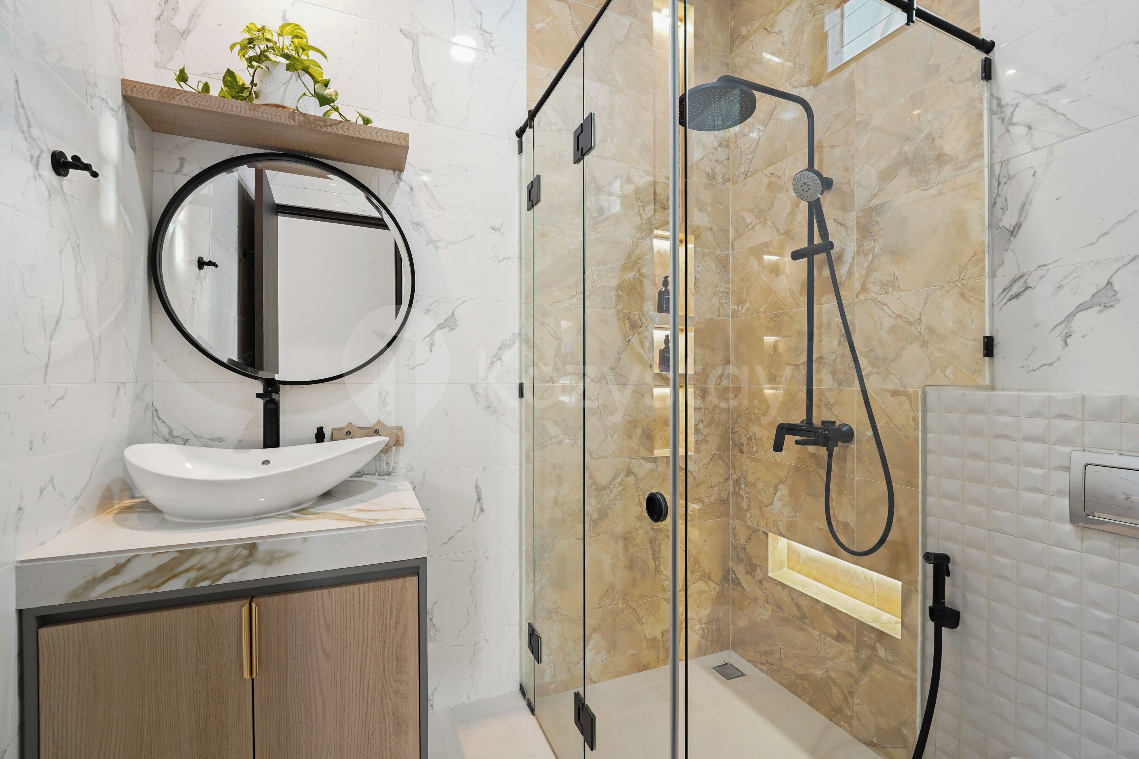 A modern bathroom with a marble vanity, a round mirror, a handheld showerhead, and a glass-enclosed shower area.