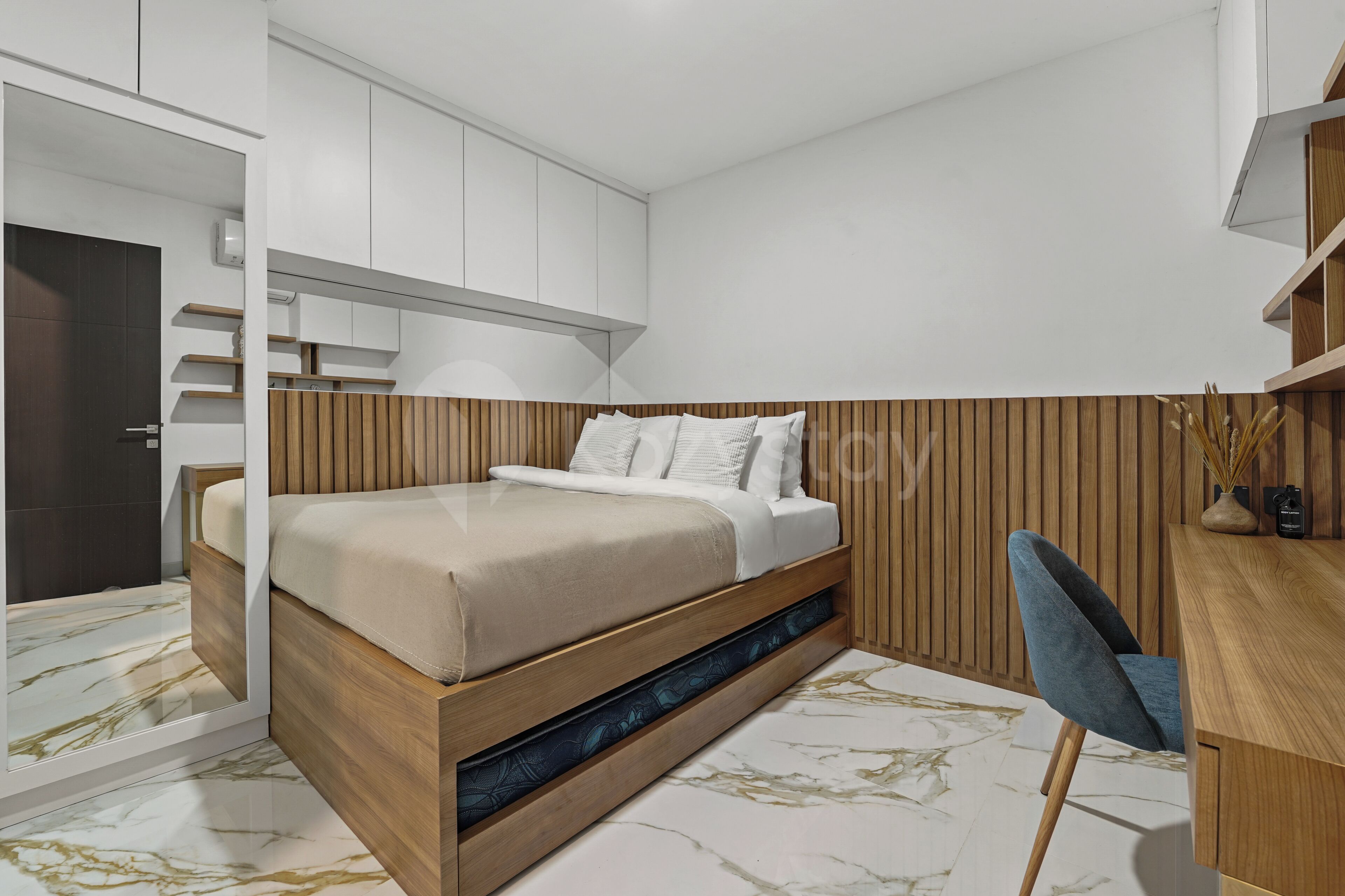 Un dormitorio moderno con cama, almacenamiento integrado, escritorio y silla.