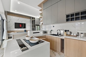Una cocina moderna con televisión integrada, cafetera y cocedor de arroz.