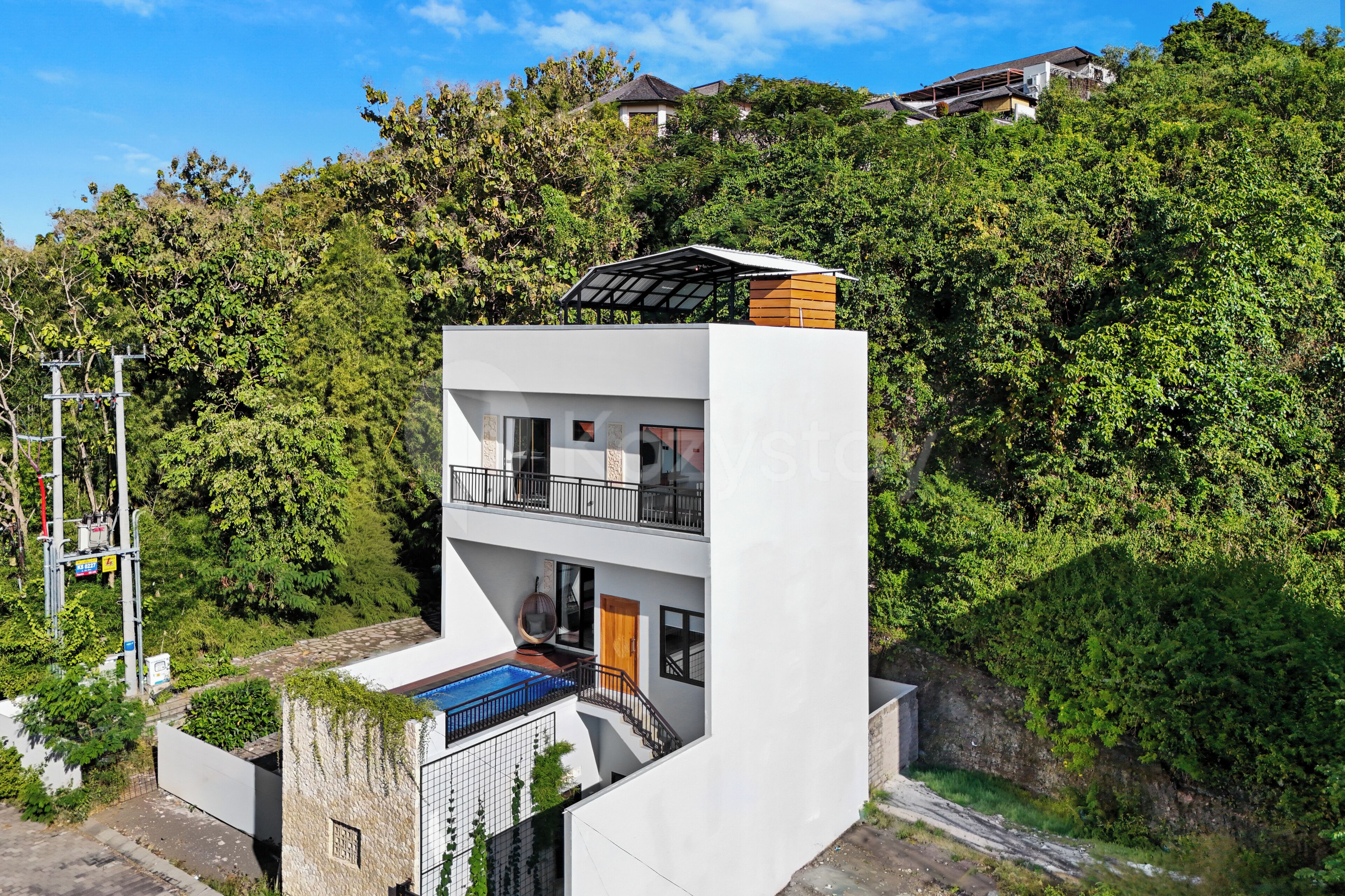 A modern two-story building with a flat roof, a balcony, and a swimming pool.