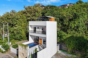 Un moderno edificio de dos pisos con techo plano, un balcón y una piscina.