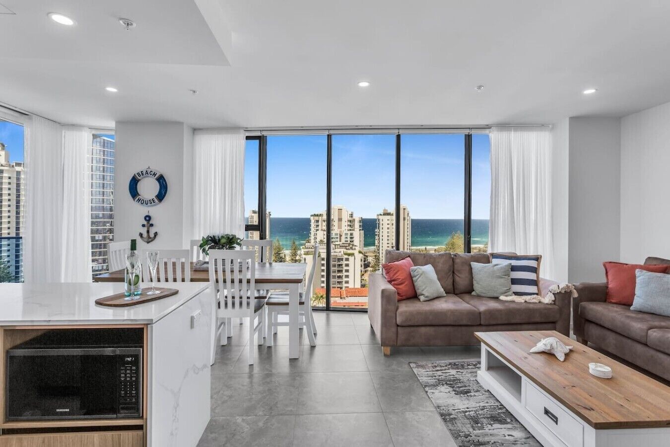 Eine moderne Wohnung mit Essbereich, einer Sofagarnitur und Blick auf Stadt und Meer.