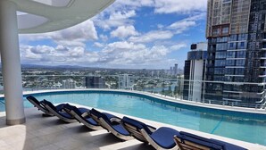 A rooftop pool with lounge chairs and a view of the cityscape. - Lvl 15 Luxury 2 Bedroom APT with Beach Views (Broadbeach)