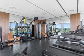 Ein modernes Fitnessstudio mit unterschiedlichen Trainingsgeräten, großen Fenstern und Blick auf die Stadt.