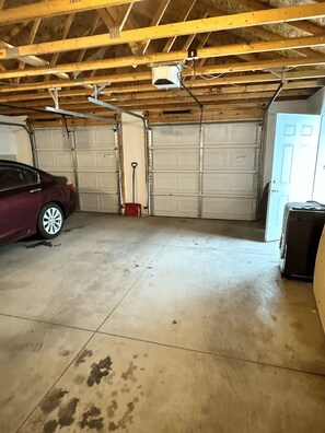 Eine Garage mit zwei weißen Garagentüren, einer roten Werkzeugkiste und einem bordeauxroten Auto.