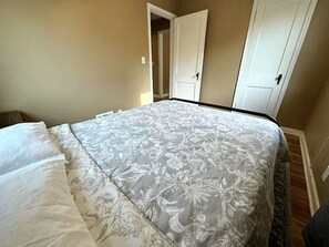 A bedroom with a bed, a door, and a carpeted floor. - Kutzky Duplex: Walk to Mayo 2BR with Free Parking (Rochester)