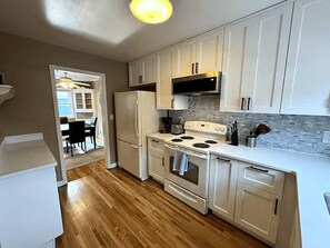 A compact kitchen with white cabinets, a refrigerator, a stove, and a microwave. - Kutzky Duplex: Walk to Mayo 2BR with Free Parking (Rochester)