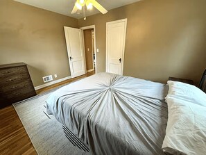 Un dormitorio con cama, cómoda y dos puertas.