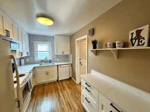 A compact kitchen with white cabinets, a wooden countertop, a built-in oven, and a small window. - Kutzky Duplex: Walk to Mayo 2BR with Free Parking (Rochester)