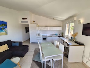 A compact living space with a kitchenette, dining area, and a sofa with cushions. - 2 bedrooms, sea view, air conditioning,all on foot (ST MANDRIER SUR MER)