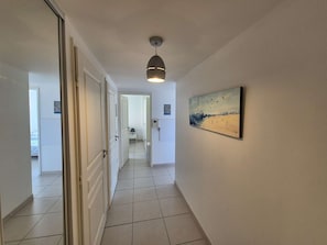 A hallway with white doors, a tiled floor, and a ceiling light fixture. - 2 bedrooms, sea view, air conditioning,all on foot (ST MANDRIER SUR MER)