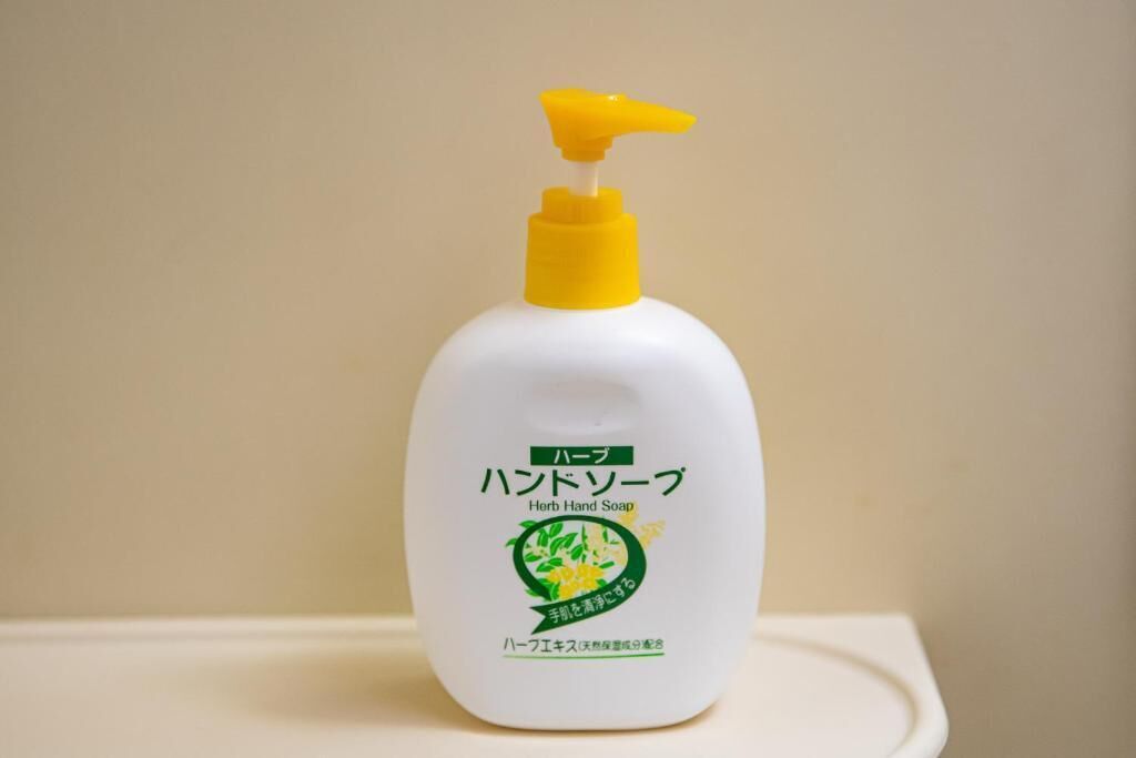 Een fles handzeep met een gele pompdispenser en Japanse tekst op een wit oppervlak.