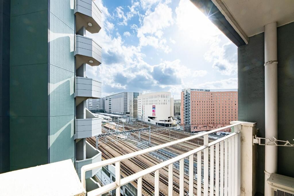 A high-rise building with a balcony overlooking a railway track and other buildings.