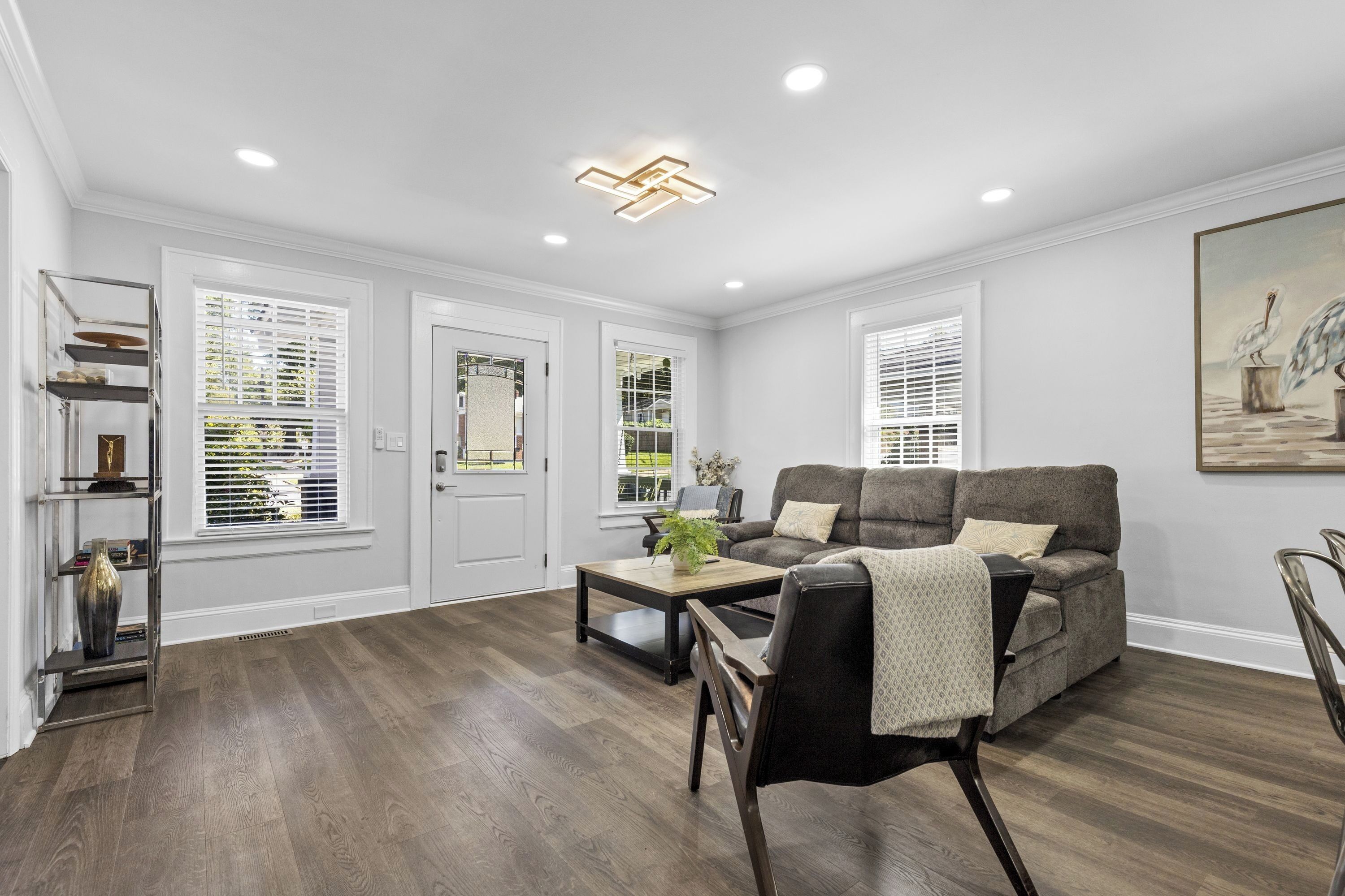 A spacious living room with a grey sofa, a coffee table, and a bookshelf.