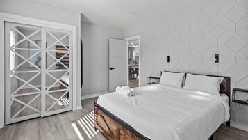 A modern bedroom with a bed, a wardrobe, and a geometric wall design.