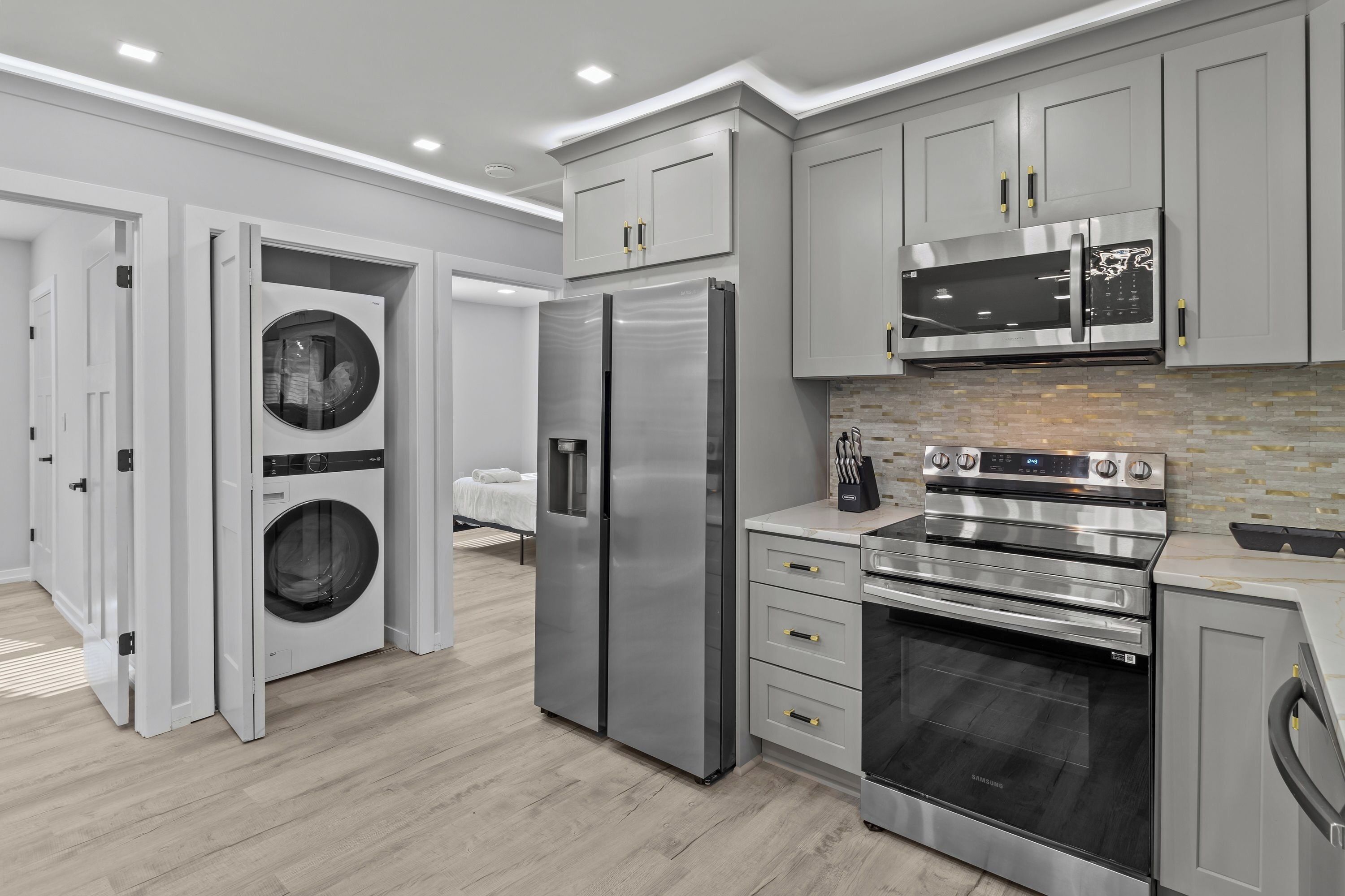 A modern kitchen with stainless steel appliances, grey cabinetry, and a built-in oven.