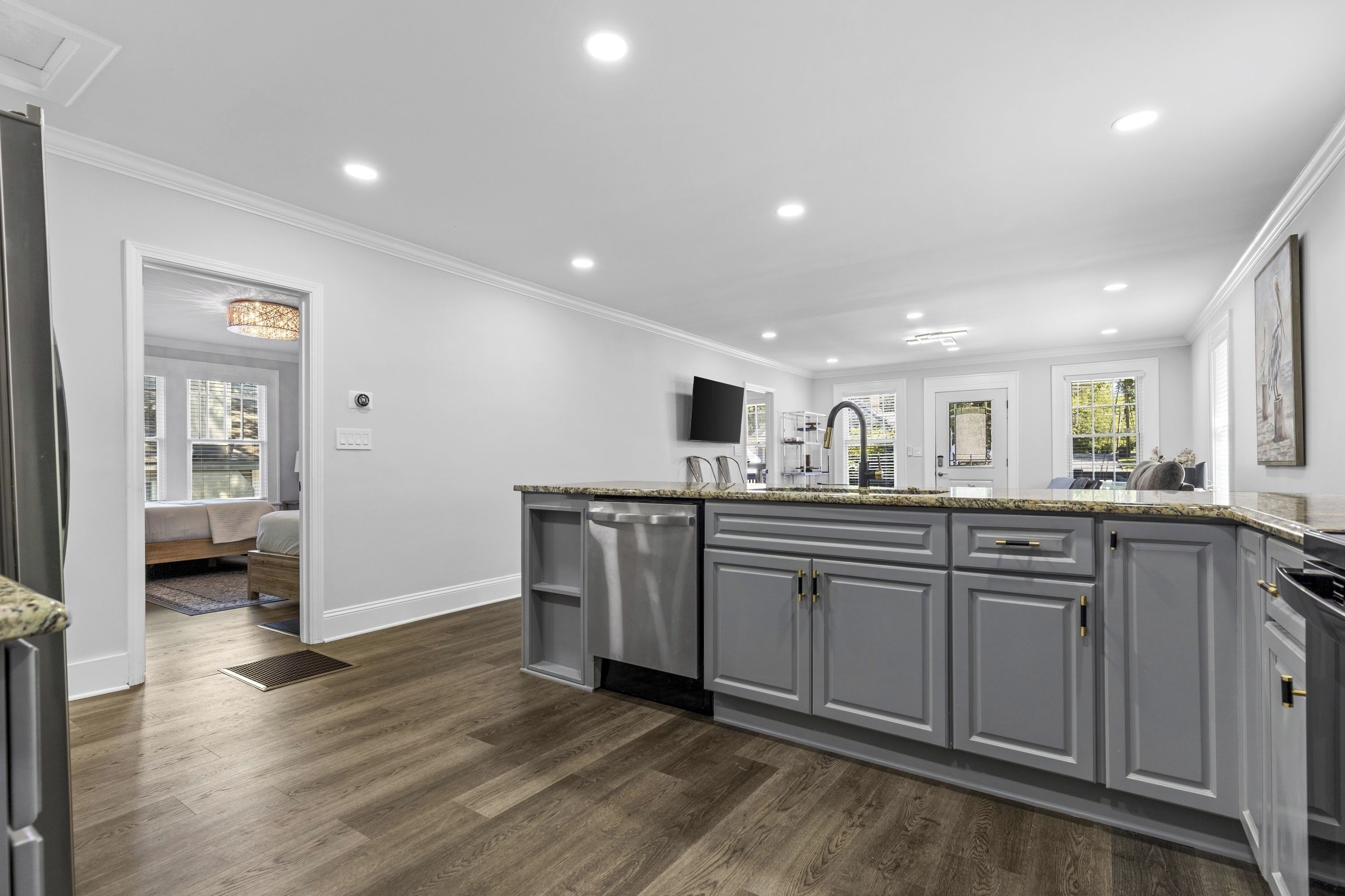 A modern kitchen with grey cabinets, a granite countertop, and a built-in dishwasher.