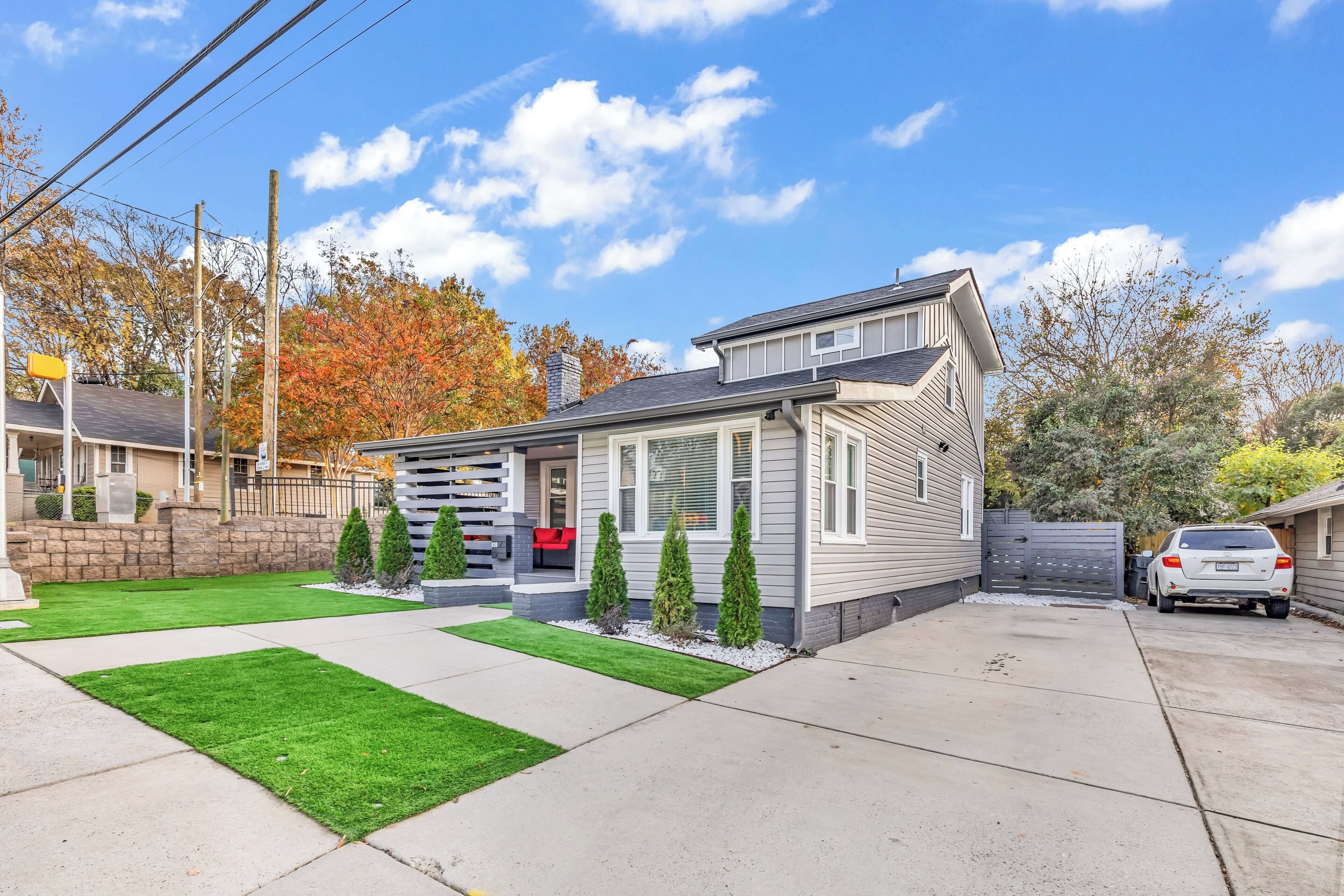 Une maison d’habitation avec un porche à l’avant, un garage et une pelouse bien entretenue.