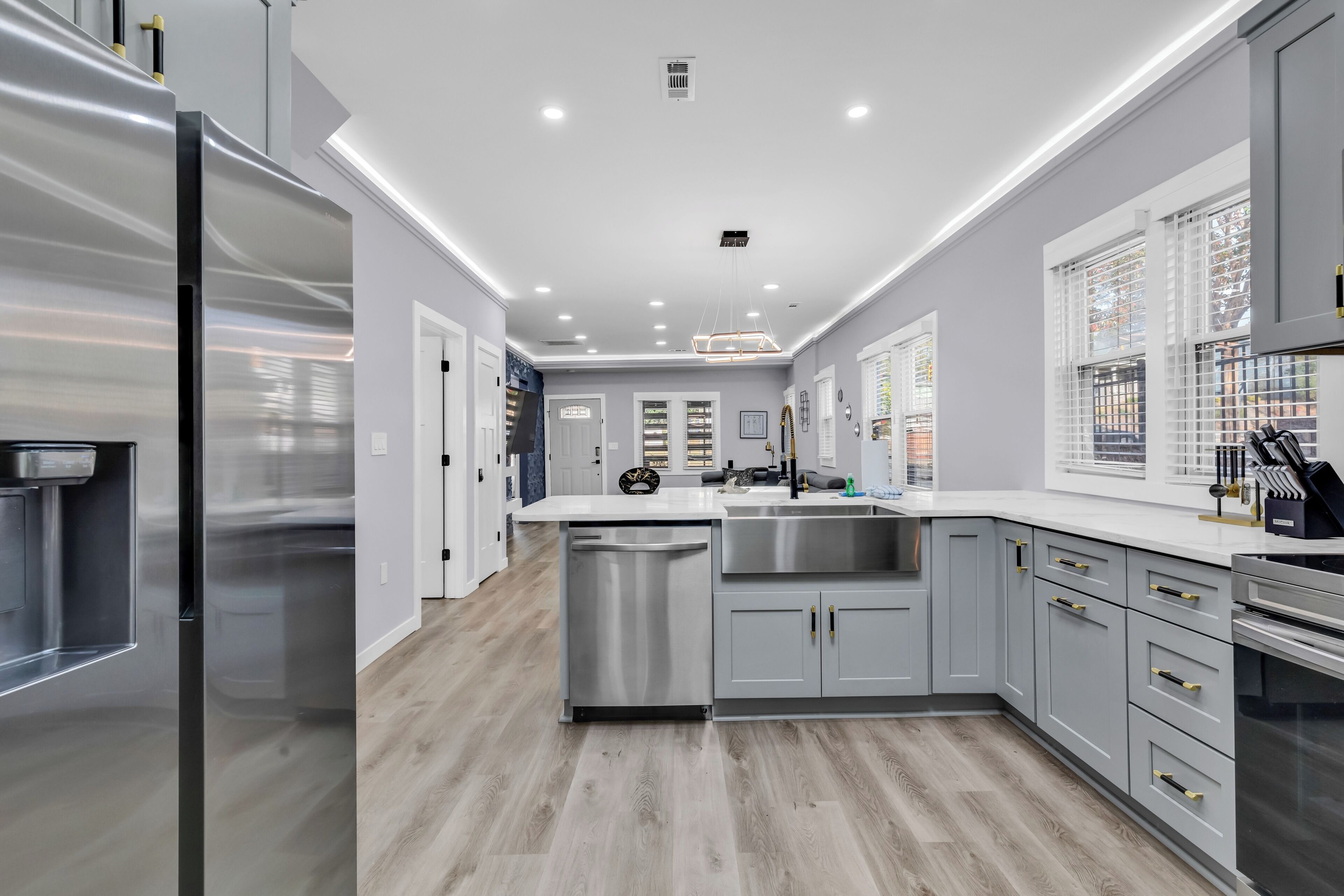 A modern kitchen with stainless steel appliances, a dishwasher, and grey cabinetry.