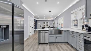 A modern kitchen with stainless steel appliances, a dishwasher, and grey cabinetry.