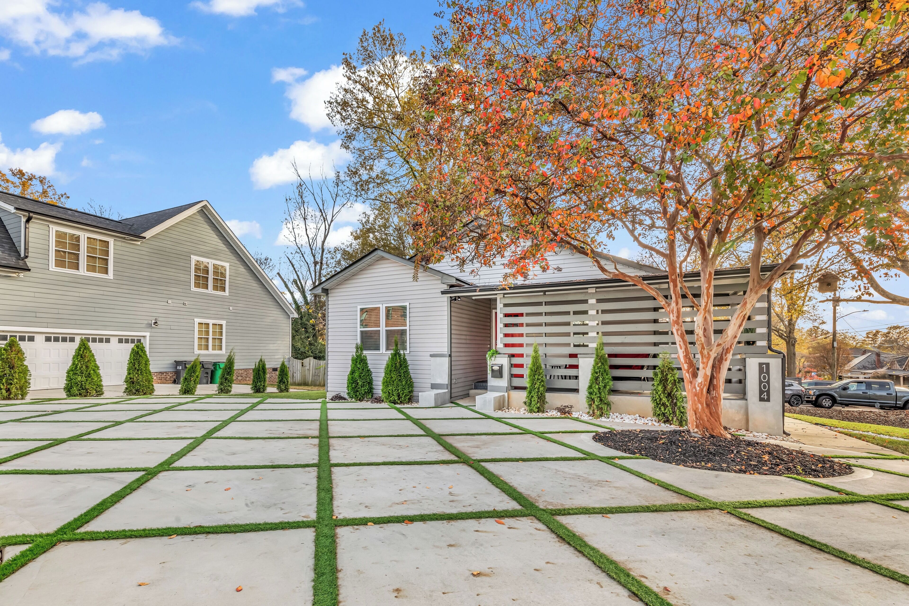 A residential driveway with a garage, a tree with autumn leaves, and a well-maintained lawn.