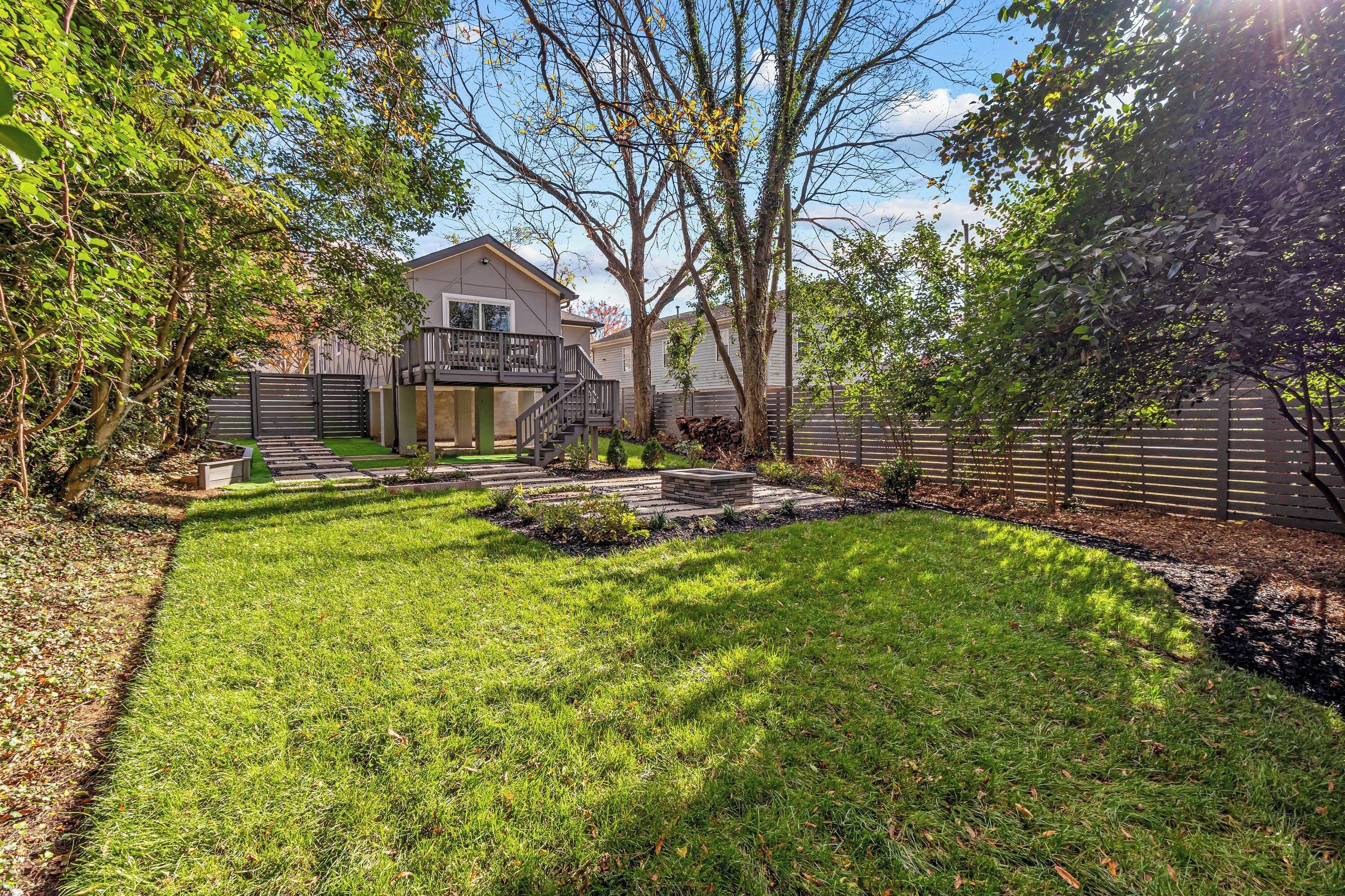A residential backyard with a lawn, a wooden deck, and a house in the background.