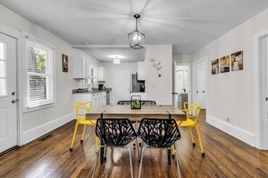 Une cuisine moderne avec des meubles blancs, une table à manger en bois et des chaises jaunes.