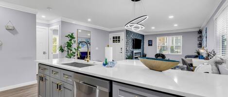 A modern kitchen with a large island, stainless steel appliances, and a contemporary pendant light.