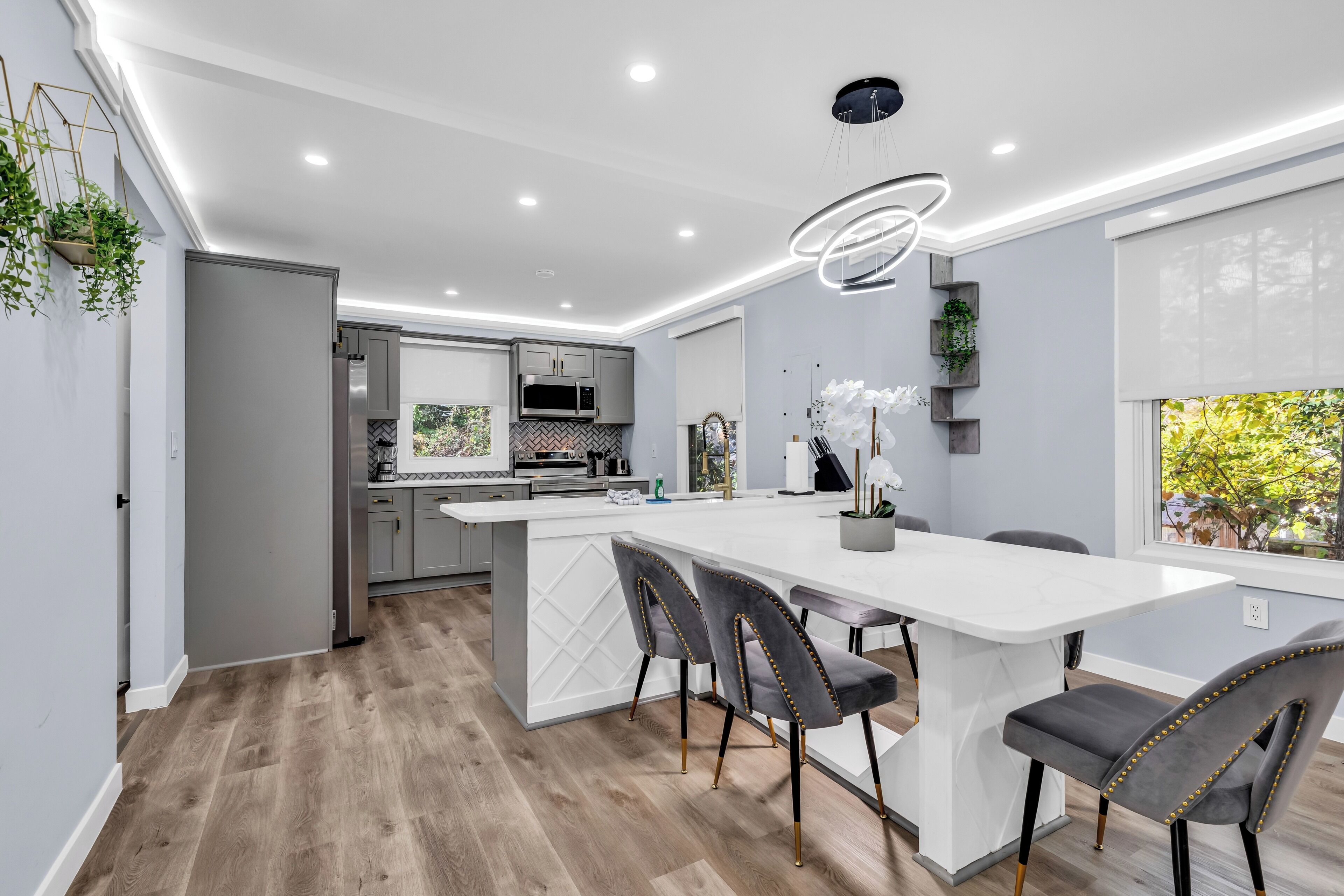 A modern kitchen with a central island, grey cabinets, and stainless steel appliances.