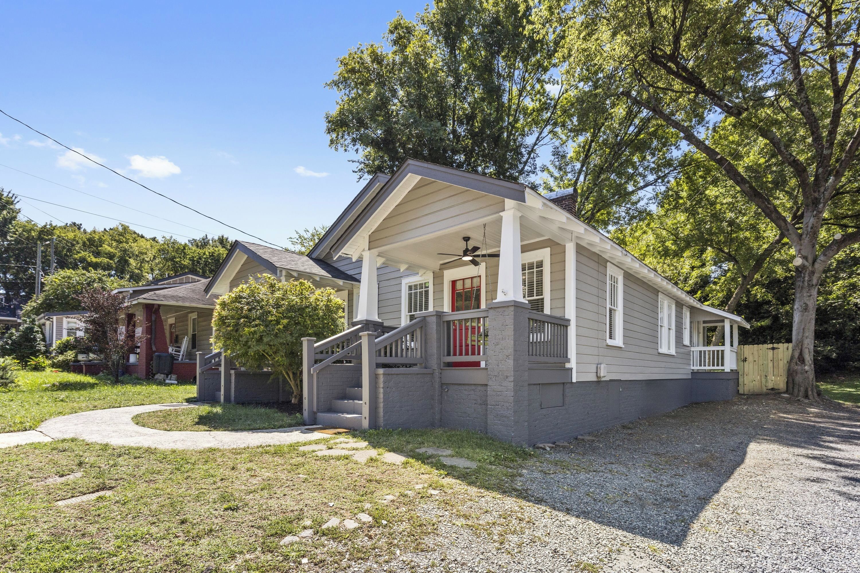 A single-story house with a front porch, a small front yard, and a gravel driveway.