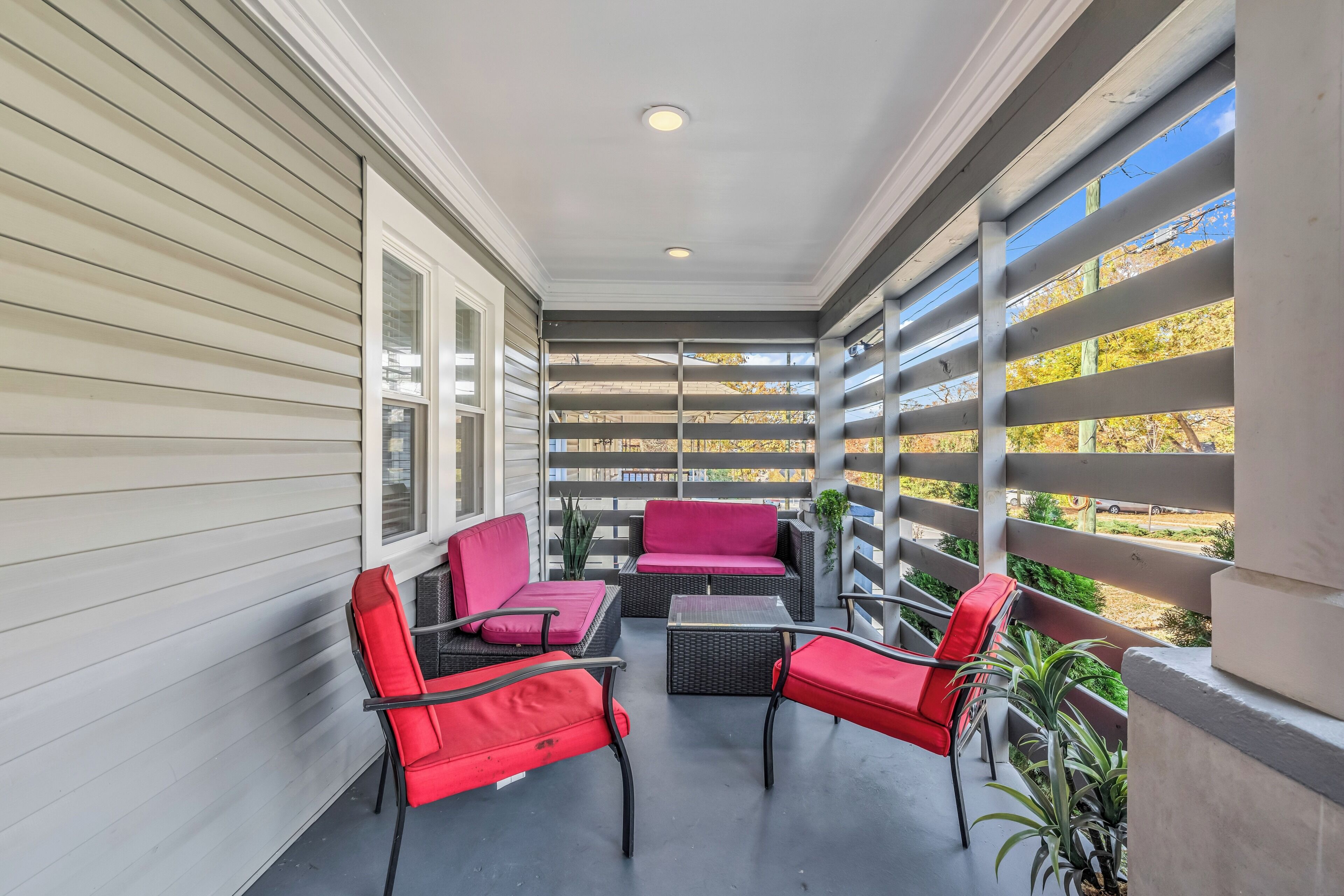 A covered patio with a seating area featuring red chairs and a table.