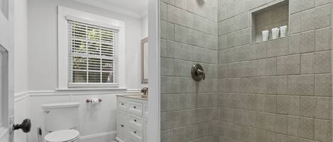A bathroom with a toilet, a sink, a shower, and a window.