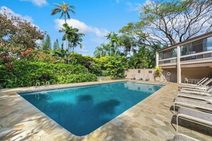 A swimming pool with lounge chairs and a two-story building with a balcony. - Hale Puka La, Luxury Oceanview for 8, Beach Access (Princeville)