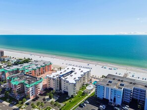 Ein Strandhotel mit mehreren Gebäuden, einem Pool und einem Strand mit Sonnenschirmen.